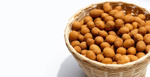 Bolas de bocadillos de maní crujientes en una canasta de bambú sobre fondo blanco.