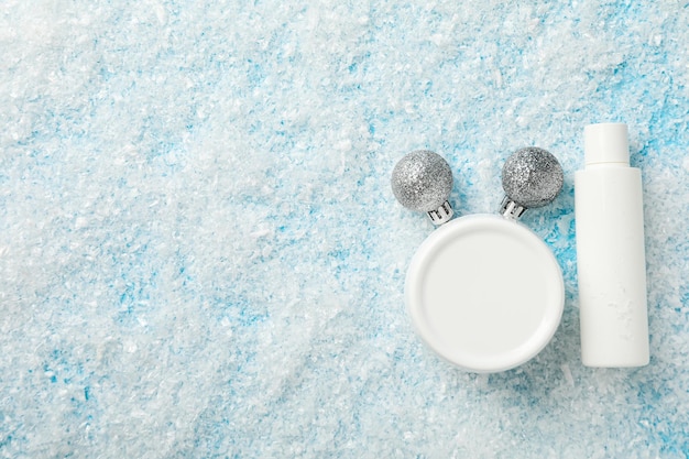 Bolas de botellas y frascos de cosméticos y nieve en el espacio de fondo azul para texto