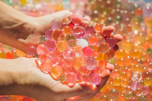 Bolas coloridas de grânulos de água, hidrogel nas mãos. experiências sensoriais