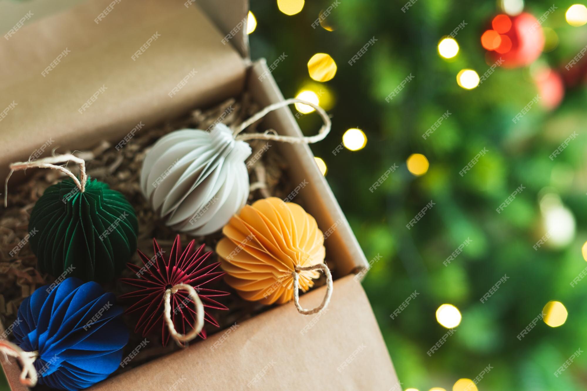 Bolas coloridas feitas de papel para enfeite de natal em uma caixa com árvore e luzes de fundo. copie o espaço. | Foto Premium Bolas coloridas feitas de papel para enfeite de natal em uma caixa com árvore e luzes de fundo. copie o espaço. | Foto Premium