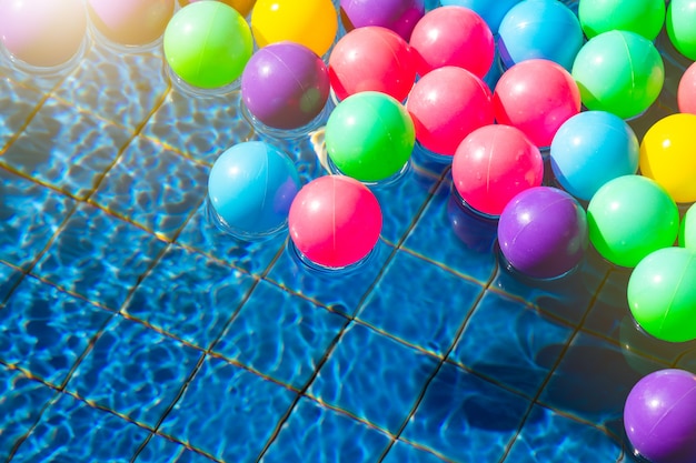 Foto bolas coloridas na piscina de manhã com espaço da cópia, verão, férias e conceito relaxante