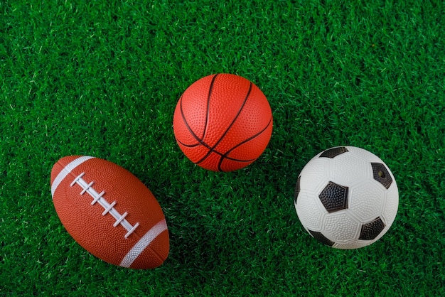 Bolas de basquete e futebol de futebol na grama verde