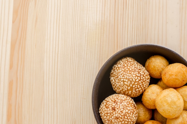 Bolas de batata doce frita em uma tigela preta na mesa de madeira