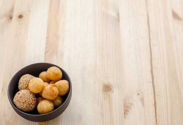 Bolas de batata doce frita em uma tigela preta na mesa de madeira