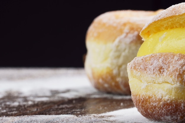 bolas de berlim conhecidas como sonho no brasil em mesa de madeira com foco seletivo de açúcar de confeiteiro