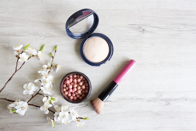 Bolas de blush e pó facial. Cosméticos de primavera. Flores de cereja