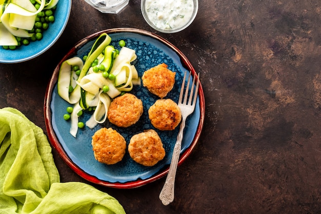 Bolas de carne de frango com salada de abobrinha e ervilhas, com molho de alho e iogurte.