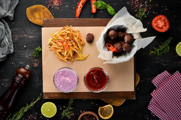 Bolas de carne frita com batatas fritas e ketchup. Em um fundo de madeira. Vista do topo. Espaço livre para o seu texto.