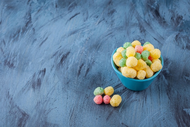 Bolas de cereais coloridas colocadas em uma tigela azul.