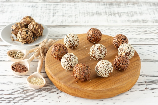 Bolas de energia crua saudáveis. Bolas de doces vegan de tâmaras, polpa de coco, nozes em uma mesa de madeira. Conceito de doces caseiros sem açúcar úteis.