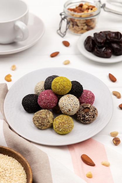 Bolas de energia de doces vegan coloridos em um prato sobre uma mesa branca.