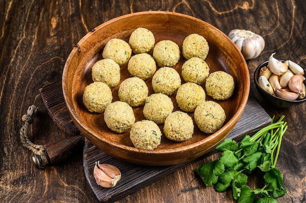 Bolas de falafel frescas e crus em um prato de madeira