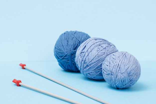 Bolas de fio de tricô e agulhas de tricô de metal em um fundo azul. Conceito de tricô.