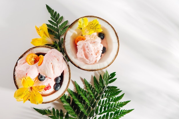 bolas de flores de decoração de sorvete e frutas em metades de coco com folhas verdes