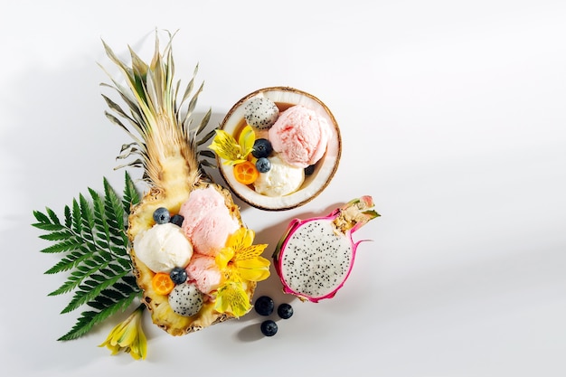 Bolas de flores de decoração de sorvete e frutas vermelhas em metades de coco e abacaxi