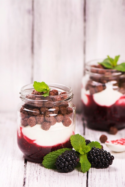 Bolas de geléia, iogurte e chocolate em potes de vidro, servidas com amora e menta.