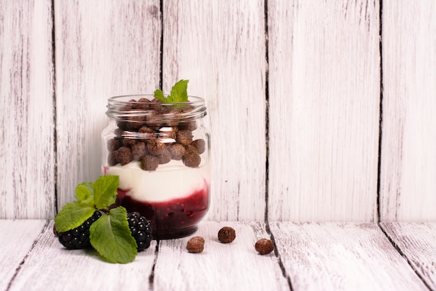 Bolas de geléia, iogurte e chocolate em potes de vidro, servidas com amora e menta.