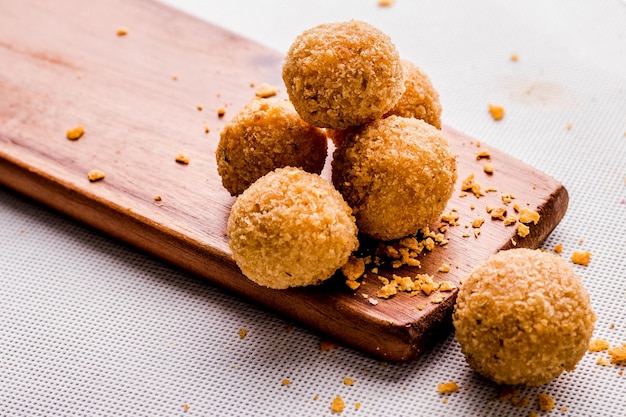 Bolas de Mac e queijo isoladas na vista lateral da placa de madeira em fastfood de fundo cinza