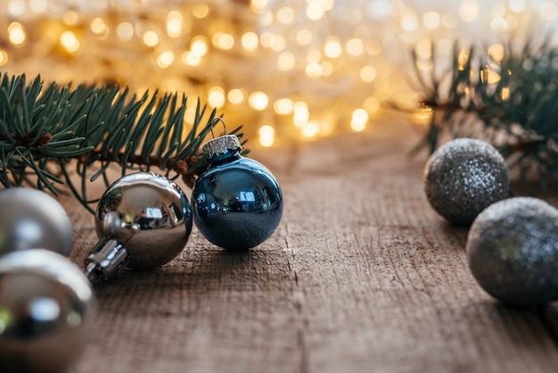 Bolas de natal azuis e prateadas em fundo de madeira com bokeh de luzes de natal