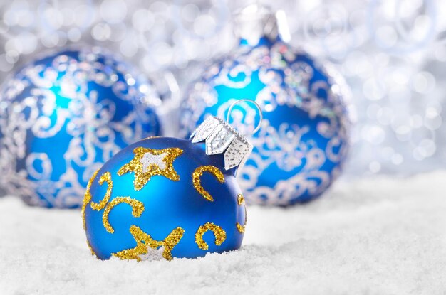 Bolas de natal azuis na neve sobre fundo desfocado