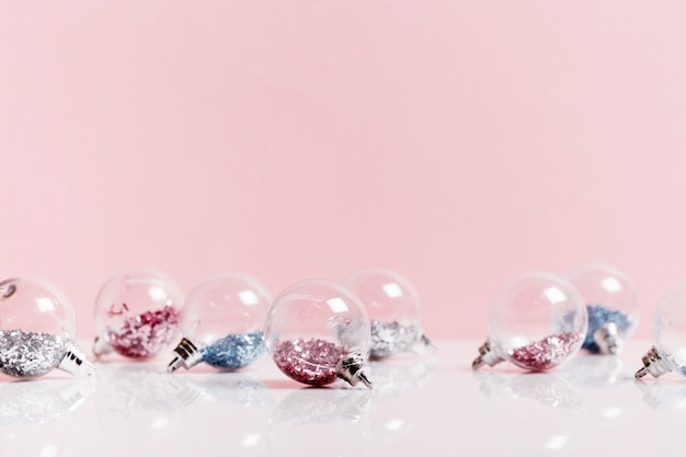 Bolas de Natal de lantejoulas rosa e azuis transparentes em fundo rosa. Composição de feriado de natal
