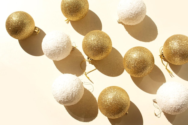 Bolas de natal decorativas douradas e brancas sobre um fundo branco. tendência de sombras contrastantes