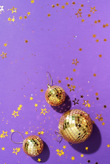 bolas de Natal douradas com estrelas brilhantes sobre fundo roxo