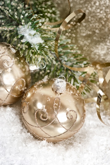 Bolas de natal douradas com galho de árvore perene no escuro da neve projetadas