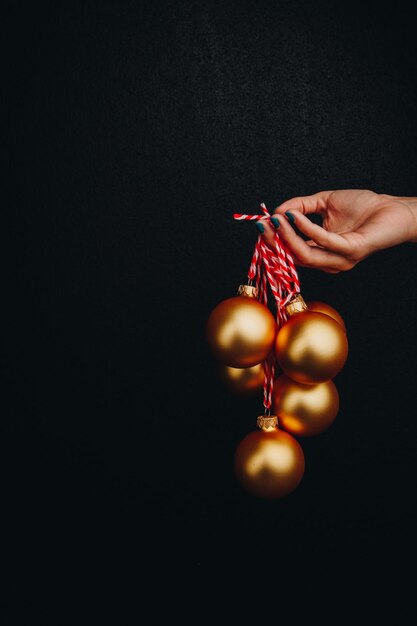 Bolas de natal douradas na mão de uma mulher isoladas em fundo preto foto de publicidade de cartão de ano novo para parabéns pela história