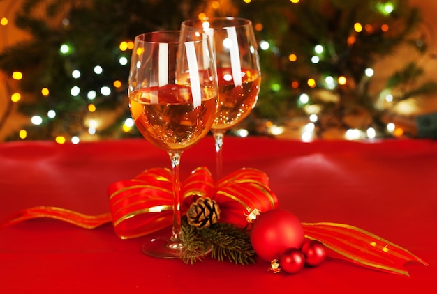 Bolas de Natal e copos de vinho com a árvore de Natal ao fundo