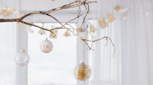 Bolas de Natal em galho dourado na janela de fundo