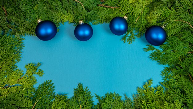 Bolas de natal festivas na fronteira com espaço para design. decoração de galhos de árvore de abeto verde bonito com decoração de enfeites de natal na bandeira azul. conceito de noel de inverno. fundo do ano novo do quadro da vista superior.