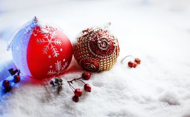 Bolas de Natal ornamentadas na neve com luz de fundo azul.