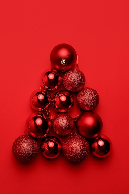 Bolas de natal vermelhas dispostas em triângulo em vermelho. vista superior, configuração plana.