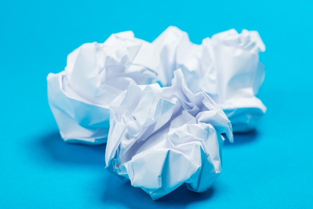 Bolas de papel amassado de cor branca sobre o fundo azul