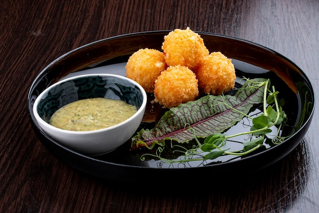 Bolas de queijo com molho de mostarda e mel Num prato preto brilhante