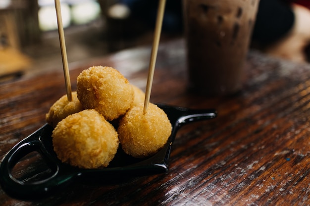 Foto bolas de queijo frito servidos na mesa de madeira no café.