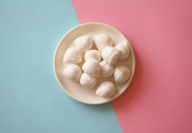 Bolas de queijo mozzarella italiano no fundo azul-rosa.