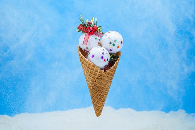 Bolas de sorvete brilhante branco de Natal no cone waffle em azul