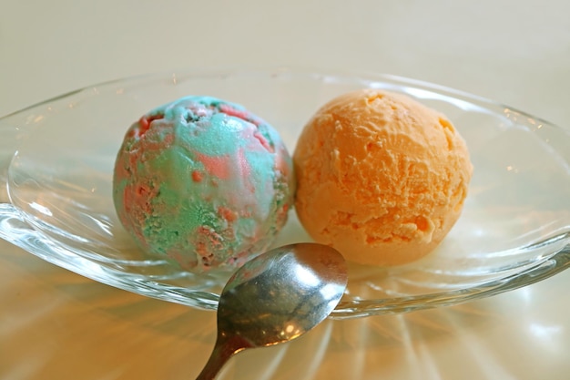 Bolas de sorvete de chiclete de cor pastel e sorvete de laranja em uma tigela de vidro
