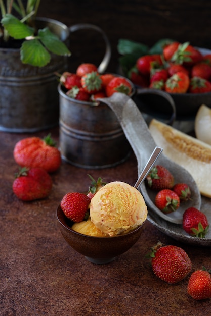 Bolas de sorvete de morangos e melões em uma xícara de cerâmica. Plante morangos em uma xícara vintage