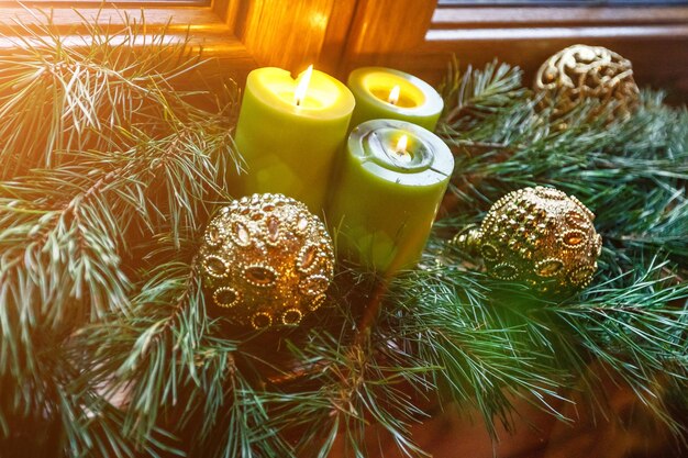 Bolas de velas de Natal e ramos de abeto no clima festivo do peitoril da janela de madeira