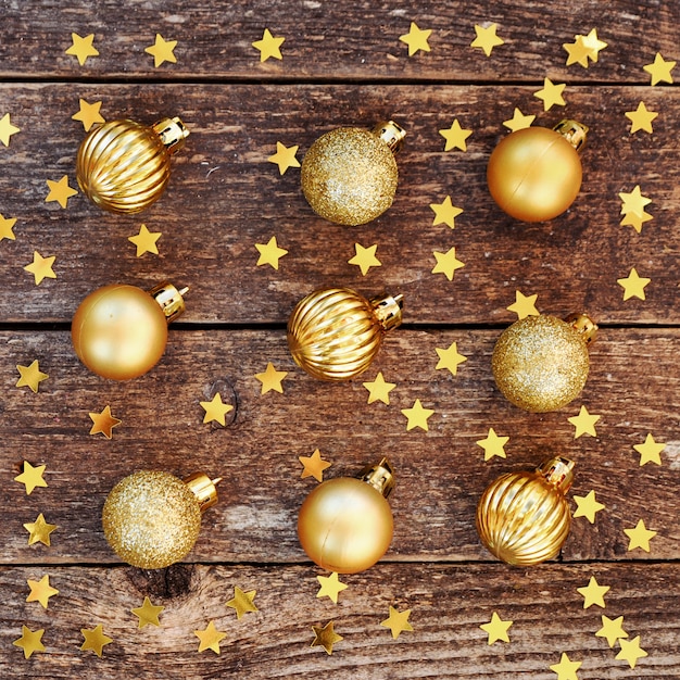 Bolas douradas e confetes estrela na mesa rústica de madeira.