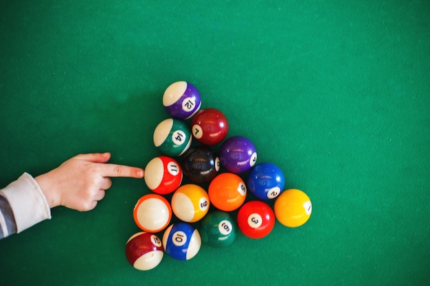 Bolas em uma mesa de bilhar em um triângulo. criança jogando bilhar