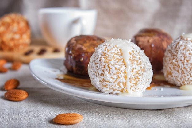 Las bolas de la energía se apelmazan con caramelo del chocolate y el coco en la placa blanca en la servilleta de lino.