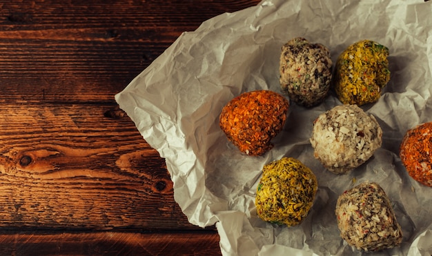 Bolas de energía cruda saludable con coco en pergamino sobre una mesa de madera.