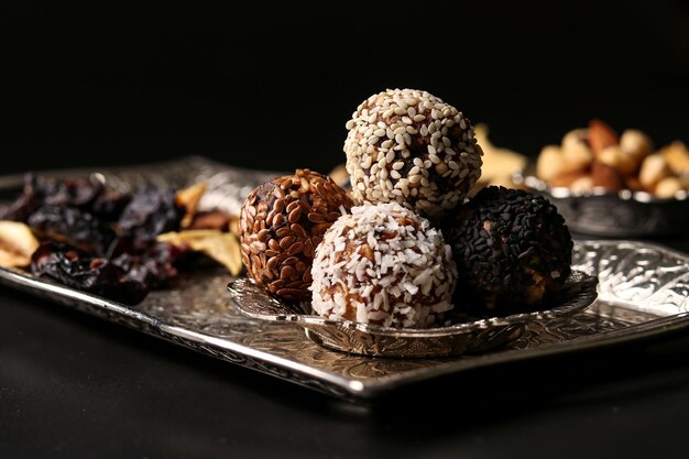 Foto bolas de energía de nueces, avena y frutos secos en una bandeja de metal sobre un fondo oscuro