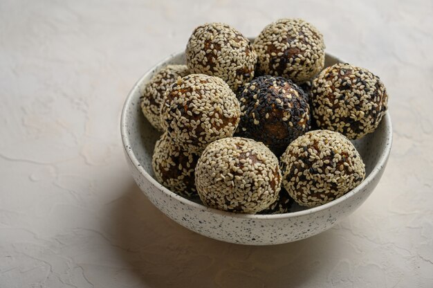 Bolas de energía saludable hechas de frutas, nueces, cacao, miel en un jarrón de luz sobre un fondo blanco.