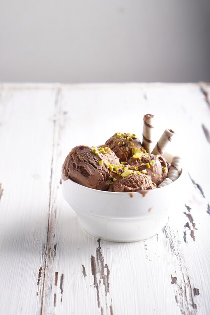 Bolas de helado de chocolate con pistacho y galletas en un tazón blanco