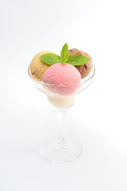 Bolas de helado con menta en un vaso transparente, sobre blanco